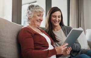  A caregiver providing senior companionship in Sacramento reads a book with an older woman.