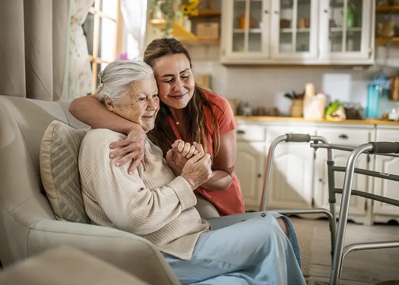 A home care caregiver in Lincoln hugs the older woman in her care.