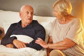 An older adult gets help from a caregiver during the first night home after a hospitalization.