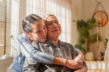 A woman hugs her mother as she tries to help with maintaining normalcy after a cancer diagnosis.