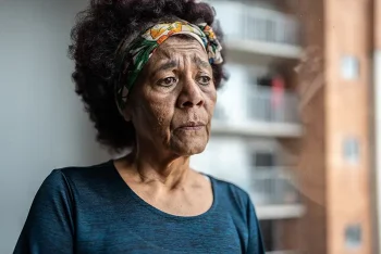 A senior woman experiencing pain symptoms stares with a weary expression.