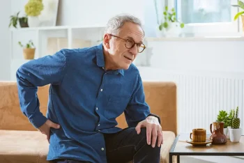 A man in need of tips for reducing chronic pain in older adults clutches his lower back in pain.